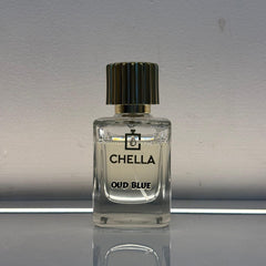 Clear perfume bottle labeled 'Chella Oud Blue' on a reflective surface with a neutral background